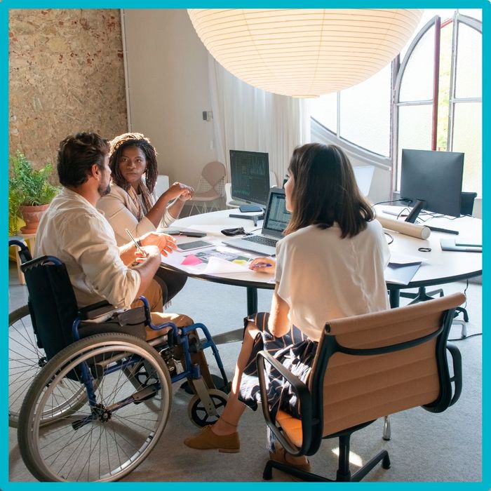 man in wheelchair talking with two women