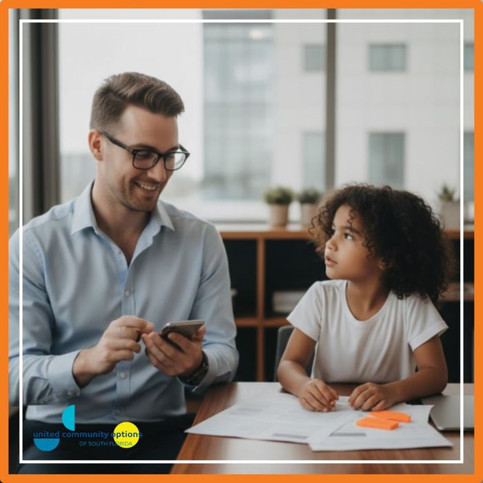 Caregiver assisting an adult with disabilities with a craft project at a table, focusing on fine motor skills development.