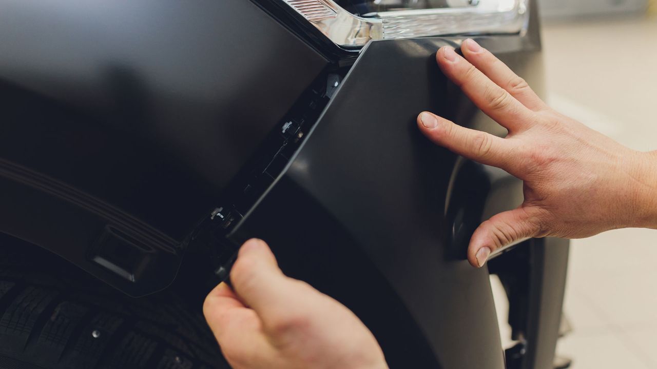 Person putting new body part on exterior of car