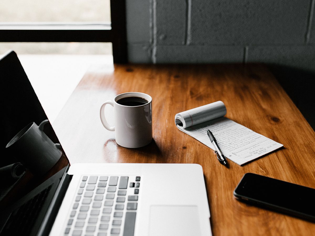 A broker’s workspace with a laptop and pen and paper.