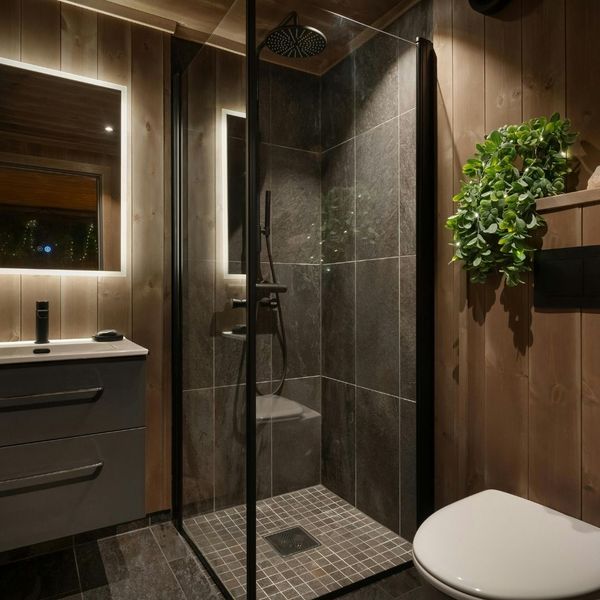 High-end residential bathroom remodel featuring wood-paneled walls, a slate tile walk-in shower, and integrated LED mirror lighting.