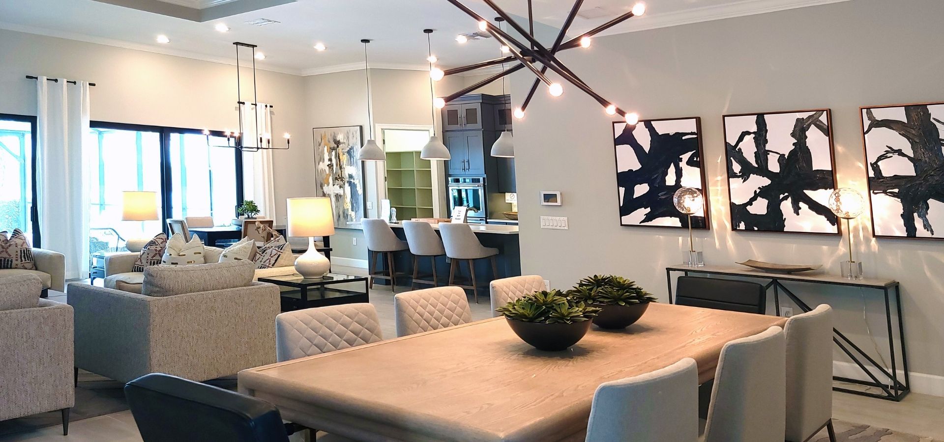 Modern open-concept living and dining area featuring high-end furniture, a designer starburst chandelier, and luxury interior finishes by a general contractor.