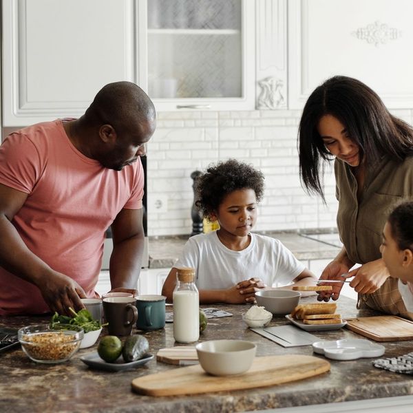 A happy family sharing a meal in a bright, modern kitchen renovated with white cabinetry and a large marble island