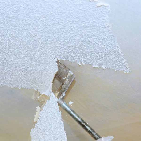 a scraper removing popcorn ceiling texture