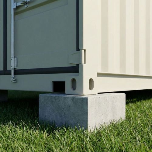 Shipping container corner elevated on a concrete block foundation.