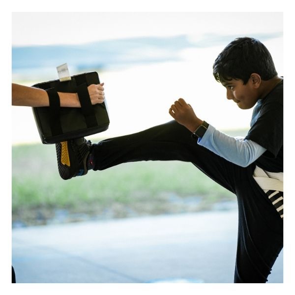 boy practicing kicks with martial arts instructor