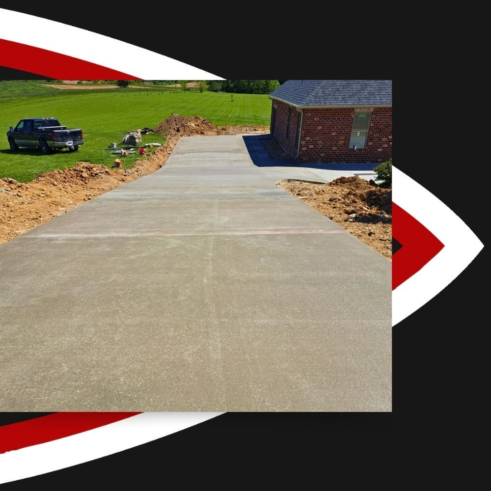 Newly poured concrete driveway beside brick home under construction.