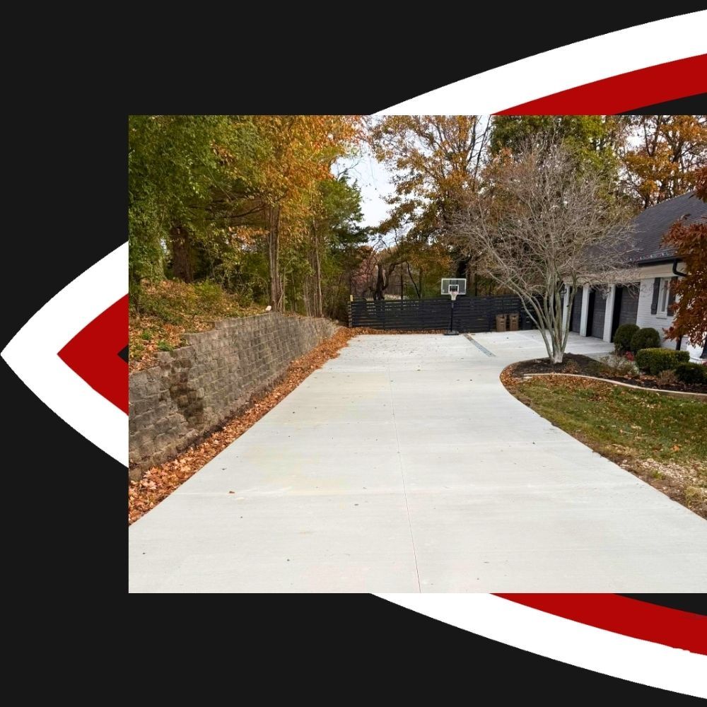 Concrete driveway alongside stone retaining wall and garage