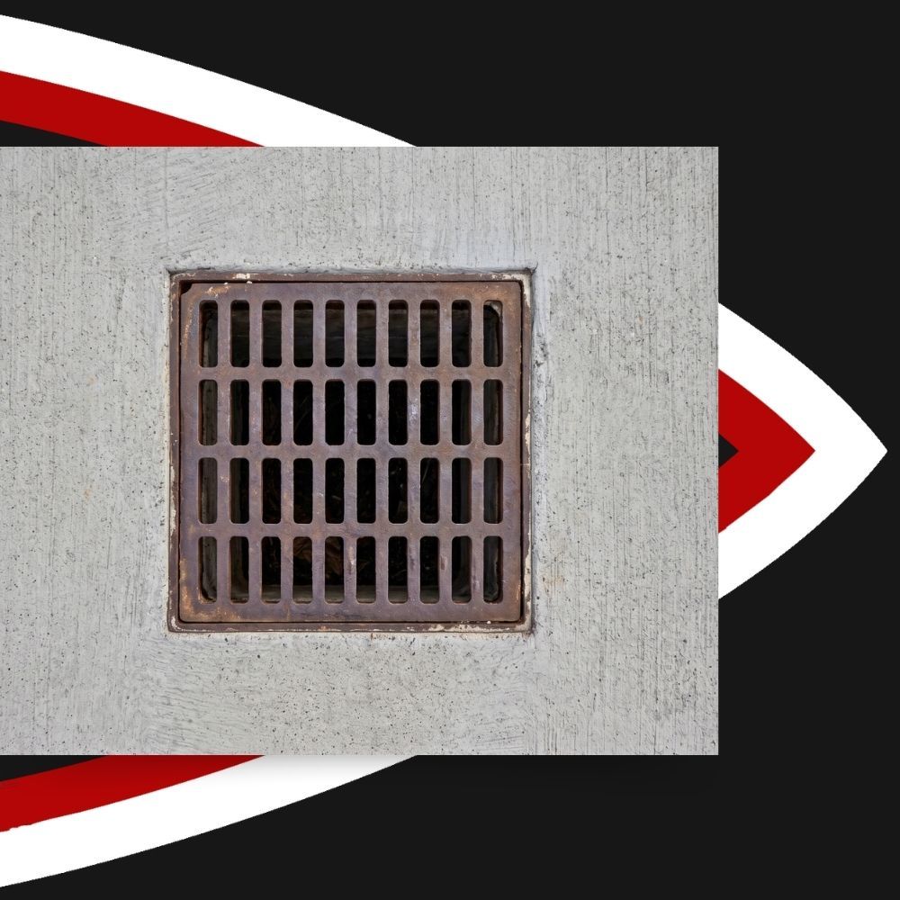 Square metal catch basin drain grate embedded in concrete flatwork