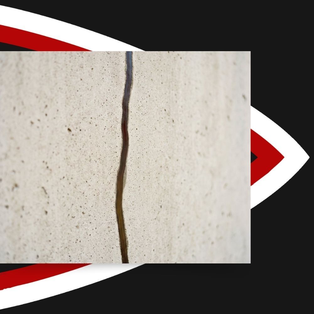 Close-up of a concrete foundation wall crack sealed with dark epoxy resin