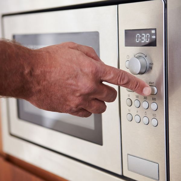 Hand pressing button on microwave