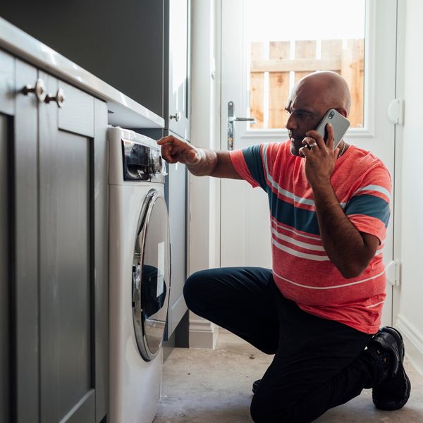 man on the phone in front of his washer