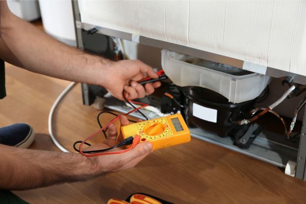a person using a multimeter on a refrigerator