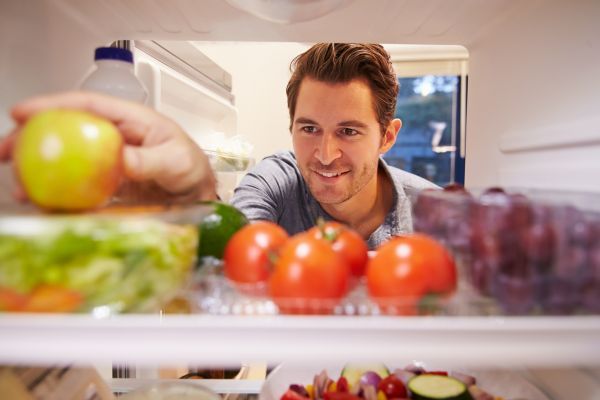 a happy man reaching into a refrigerator 