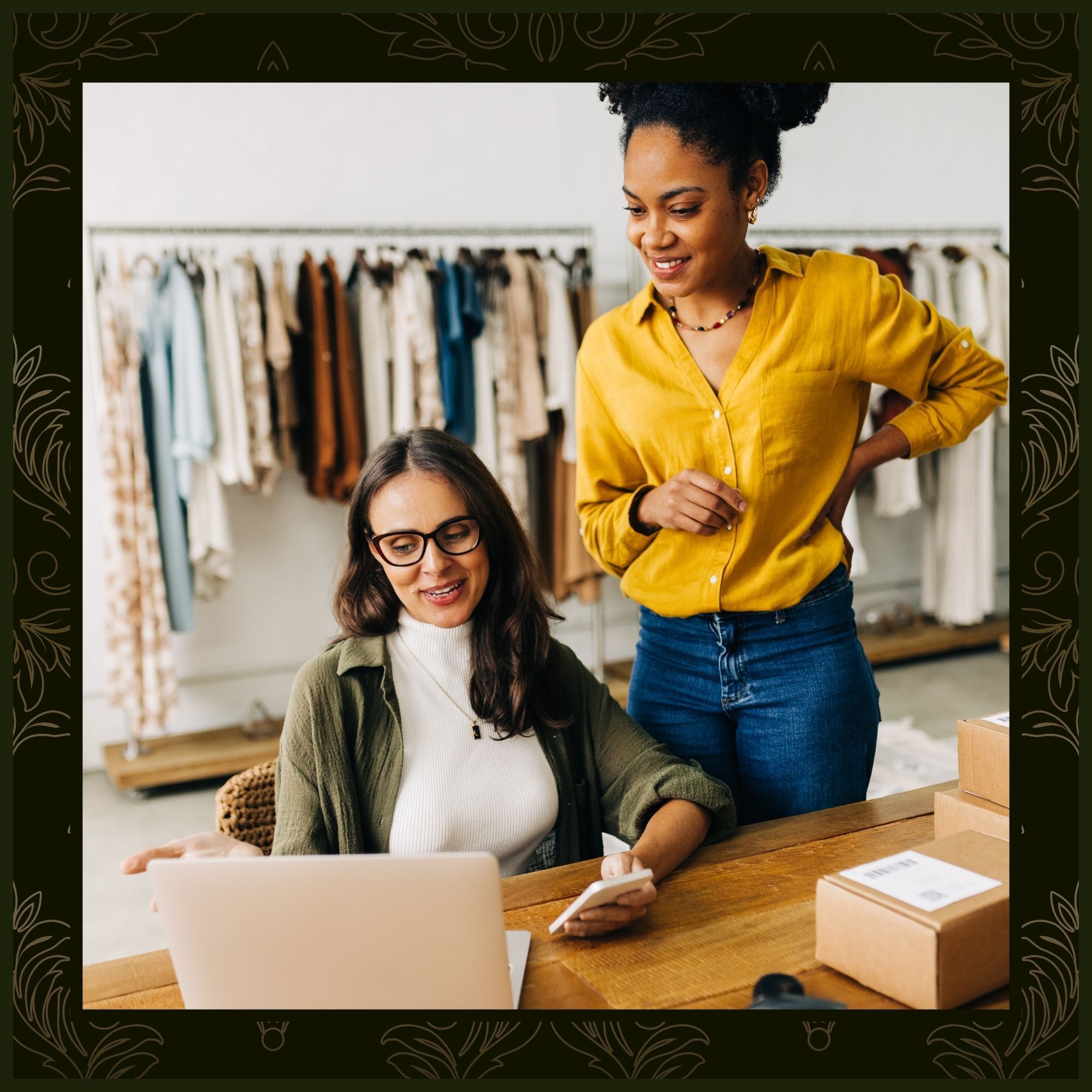 Two women in a retail clothing boutique discussing information on a laptop, framed by a dark green decorative border.