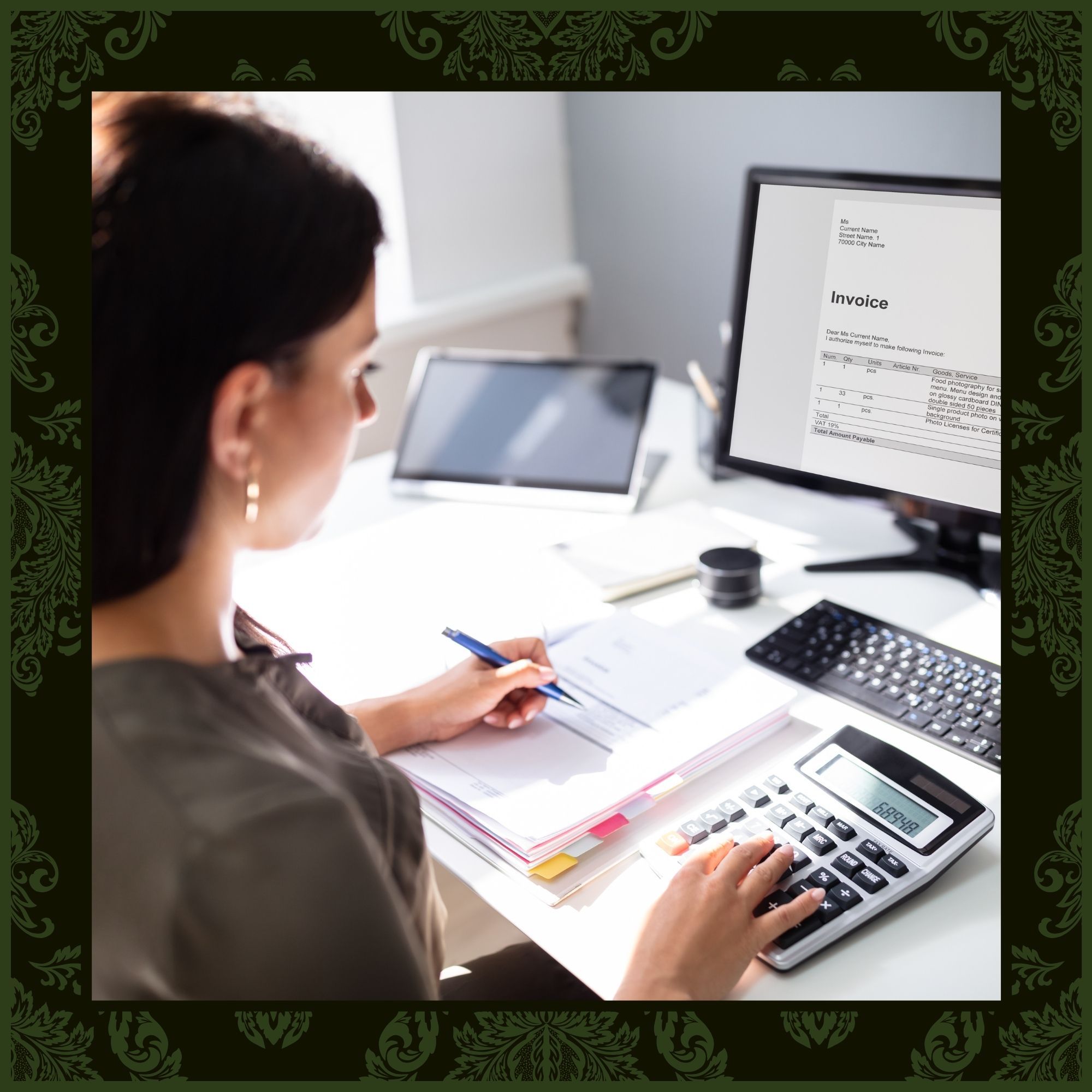 An over-the-shoulder view of a woman working at a bright desk, using a large desktop calculator while reviewing an invoice displayed on her computer monitor.