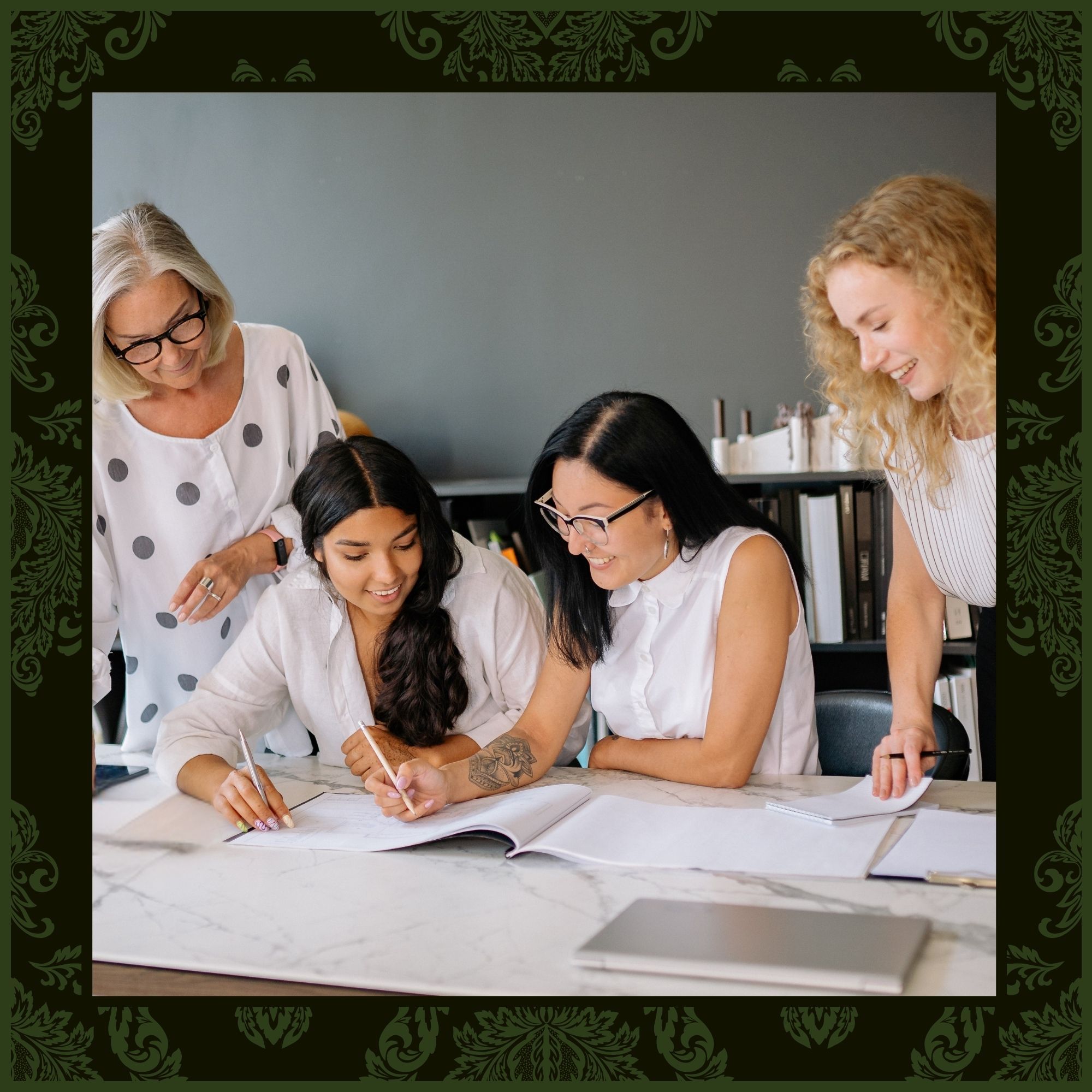 Four women of diverse ages and backgrounds collaborating at a white marble table, reviewing a large ledger together in a professional office setting.