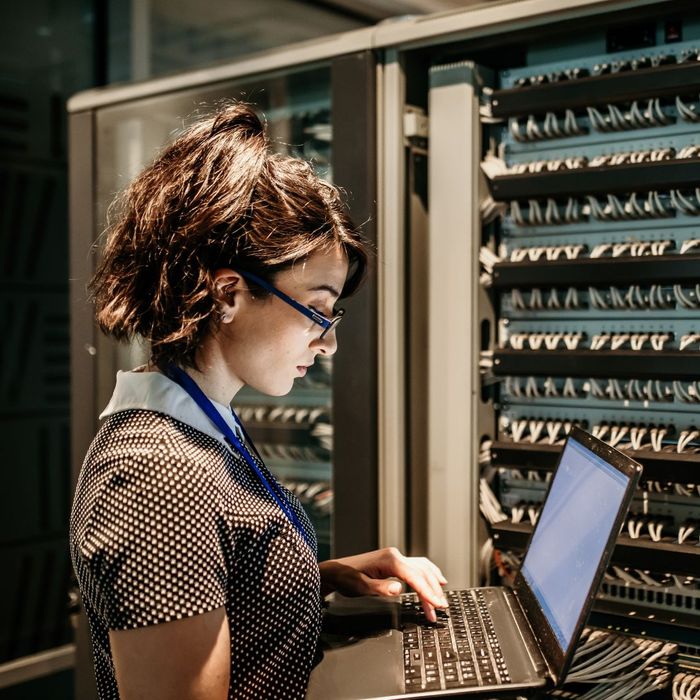 A woman with a computer working on servers