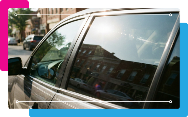 Close-up of a car’s side window with a dark, reflective tint
