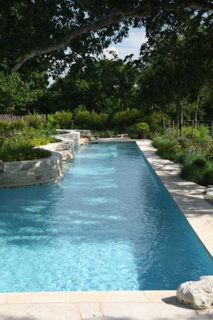 Photo of a pool surrounded by greenery and stone masonry