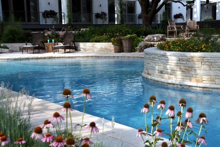 Photo of a poolside with lounge chairs, plants, and stone masonry