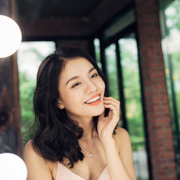 A happy person smiling at their radiant, healthy skin reflection in a mirror. happywoman.jpg