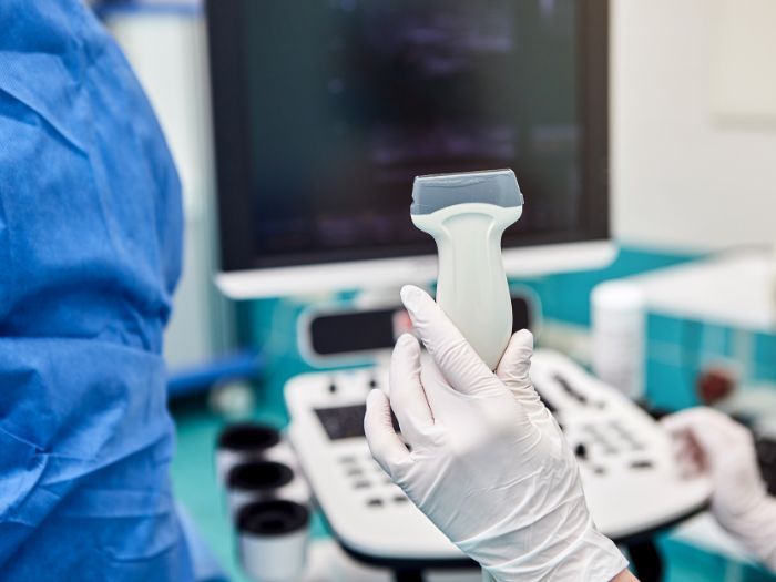 Gloved medical professional's hand holding an ultrasound wand