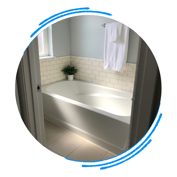 A simple, clean bathroom with a new white bathtub, a tile backsplash, and a towel on a rack.