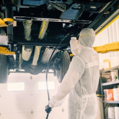 Professional applying undercoating to a vehicle. 