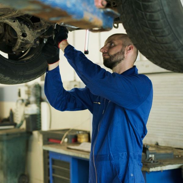 man inspecting vehicle underbody