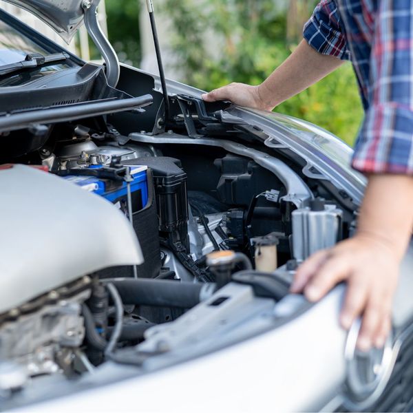 man looking into open hood of vehicle