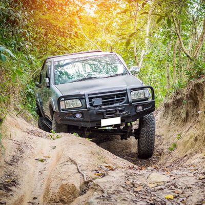 Older truck driving over large rocks. 