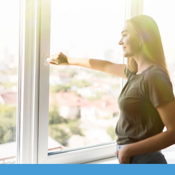 A woman breathing in fresh air from her window