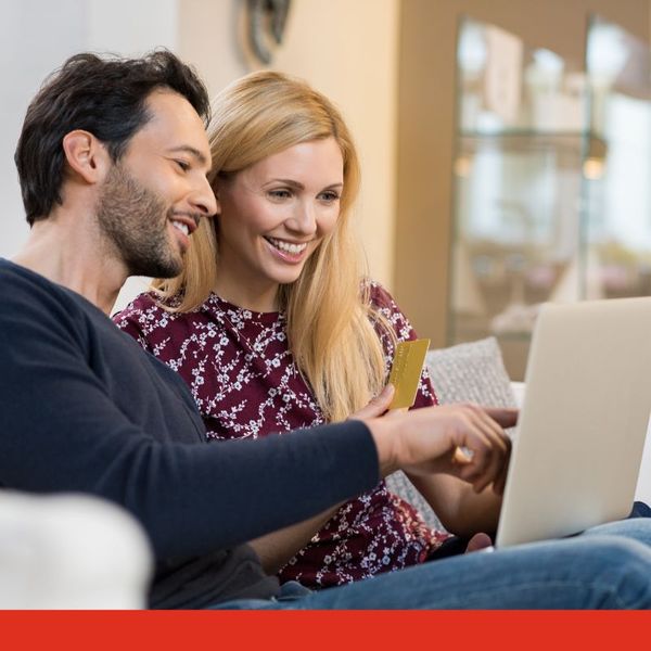 A couple looking at their bills on a laptop and smiling