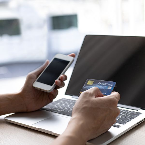 Hands holding a credit card while using a laptop
