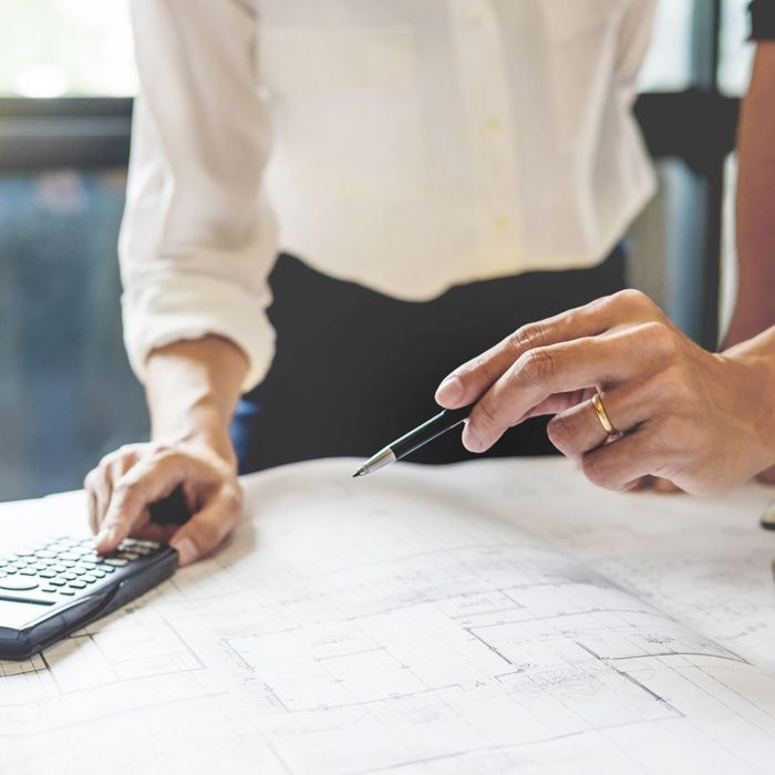 Two people pointing at blueprints