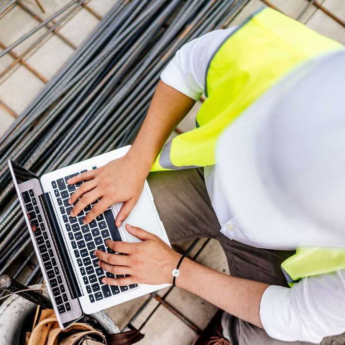 overhead view of construction worker on worksite using laptop
