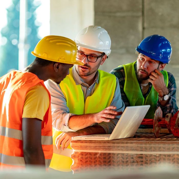 3 construction workers discussing over laptop