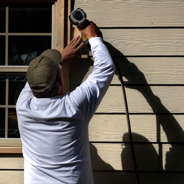 a man stapling siding to a home