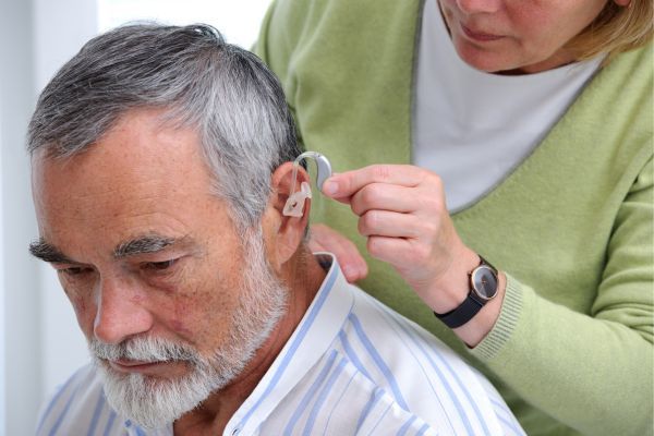 woman helping a man with his hearing aid