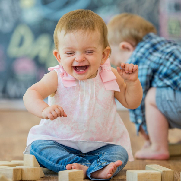 a toddler giggling  in front of blocks