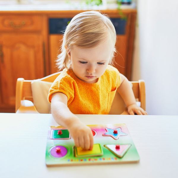 Little girl playing with a shape puzzle