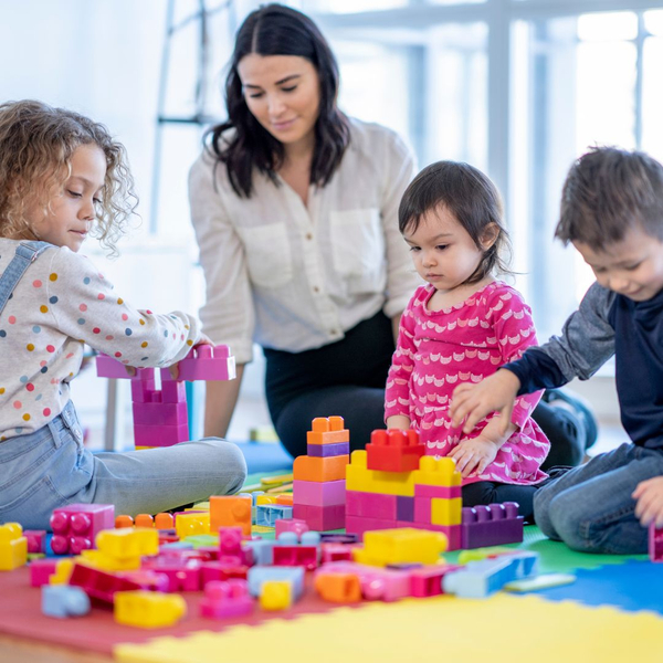 Daycare worker watching children play with blocks