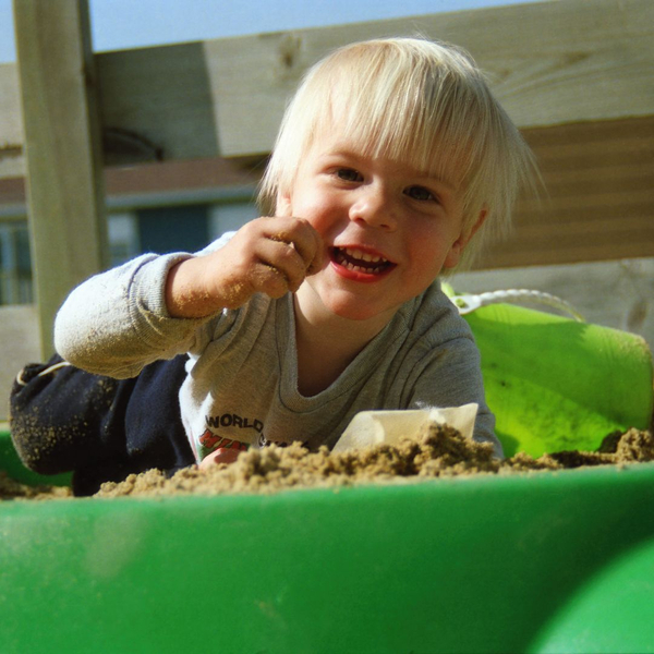 toddler playing in a sandbox, sifting sand through their fingers.