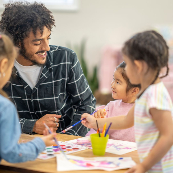 Daycare worker helping children use watercolor paints