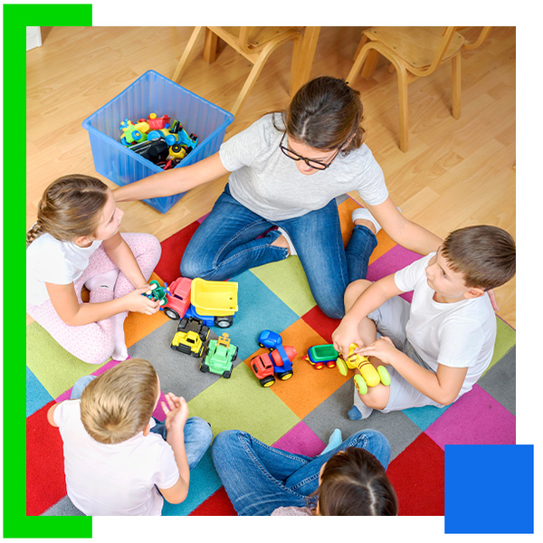 An image of 4 children and their teacher sitting on the floor and learning at preschool
