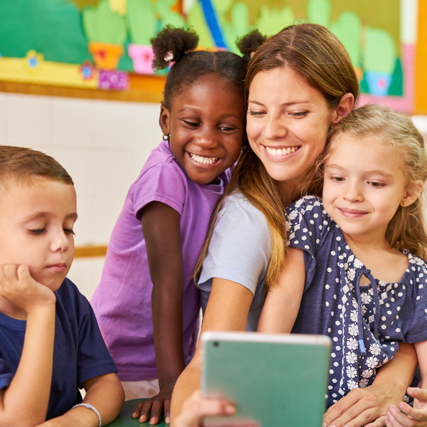 teacher with students around her looking happy. 