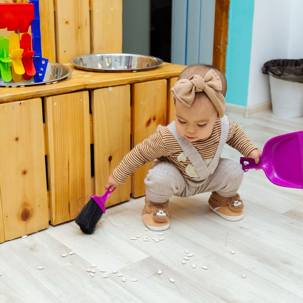 a toddler sweeping up a small spill