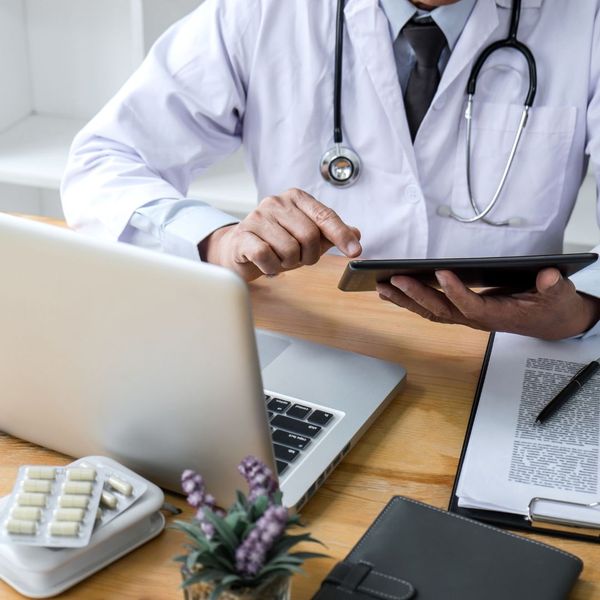 Doctor looking at a tablet and a laptop