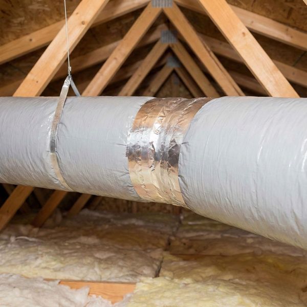Insulated HVAC ductwork suspended in a residential attic with sealed joints to prevent heat loss.